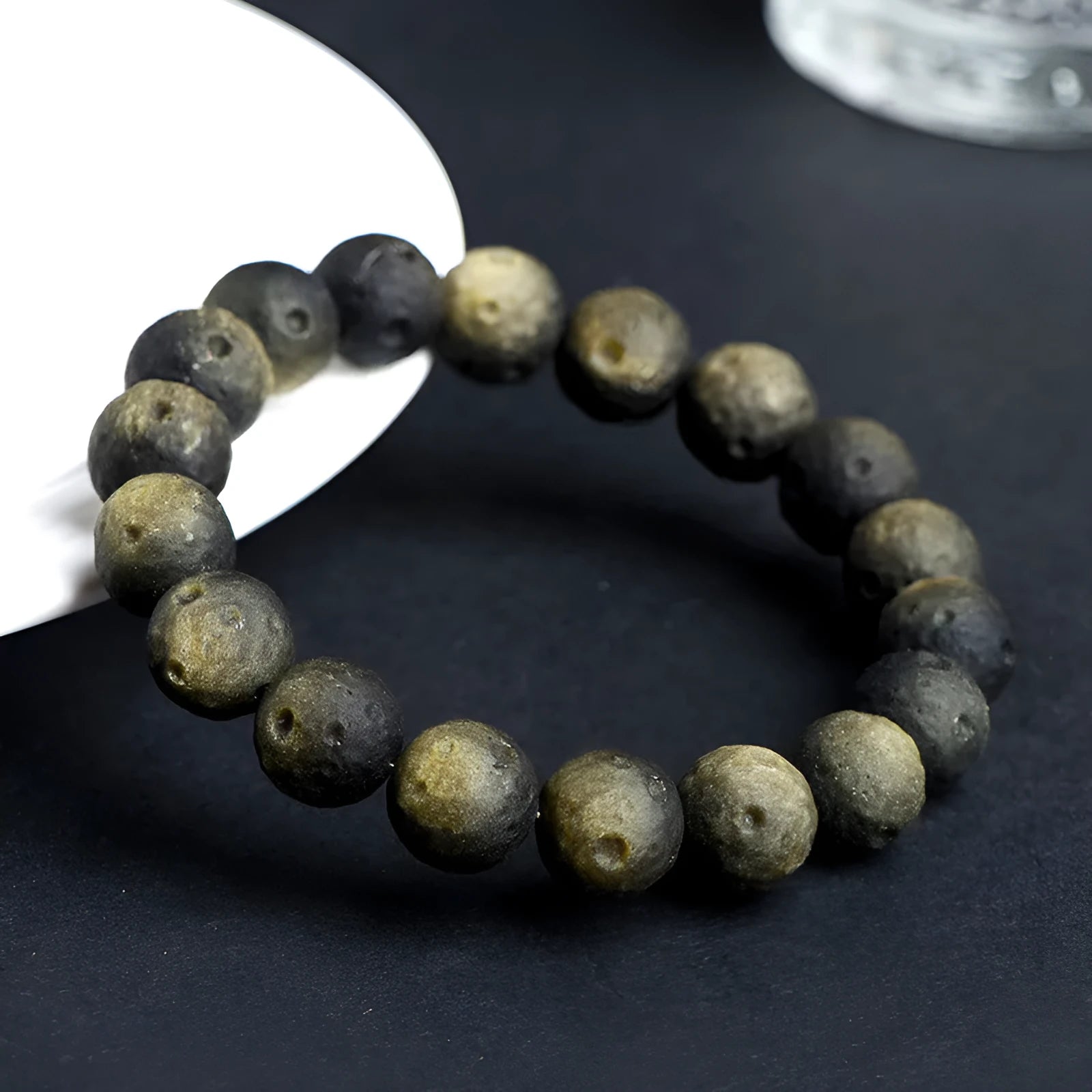 Natural obsidian crater ball bracelet with textured beads in gold or silver stone finish on a wrist.