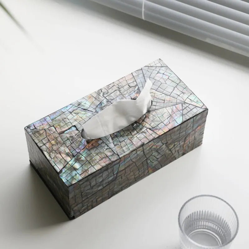 A black square natural shell storage box with a removable white internal organiser on a wooden table.
