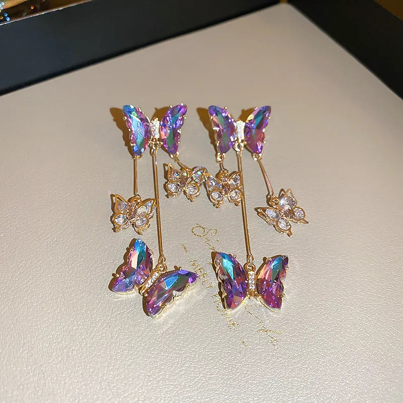 A pair of blue purple butterfly tassel earrings with silver needle crystal flowers on alloy posts.
