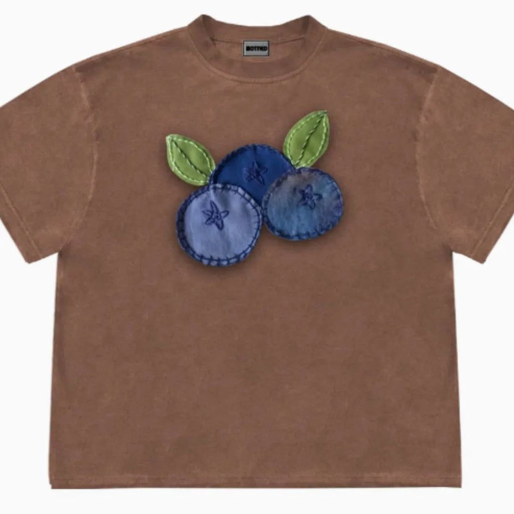 A loose-fitting blueberry and floral patchwork short sleeve t-shirt on a hanger.