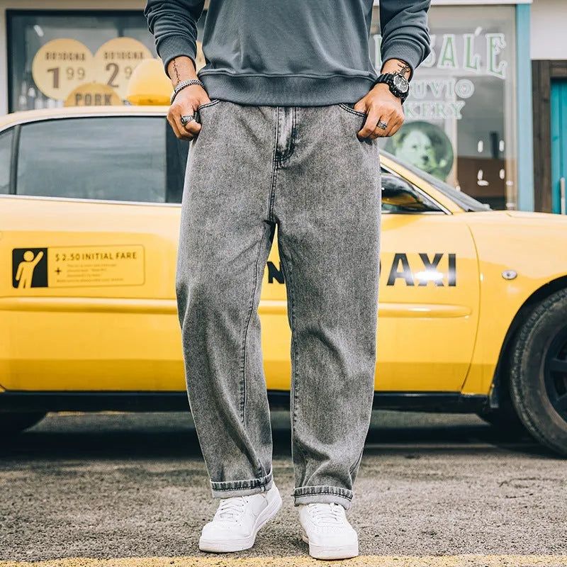 Men's dark blue loose straight-leg casual jeans on a hanger, showing mid-waist and zipper fly.