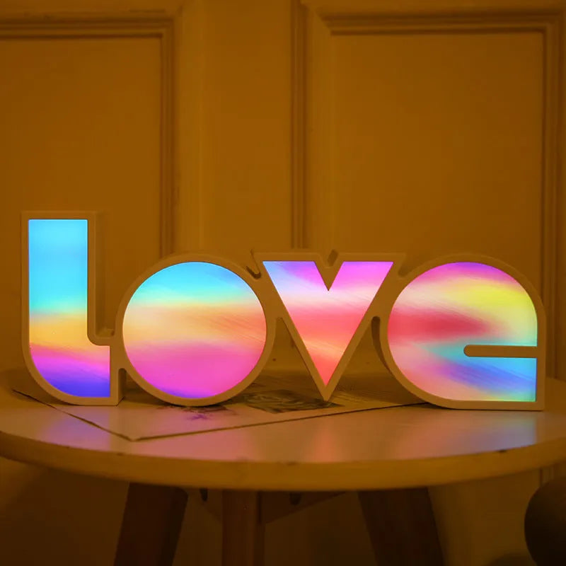 Rainbow style plastic LED decorative light spelling LOVE, shown on a table.