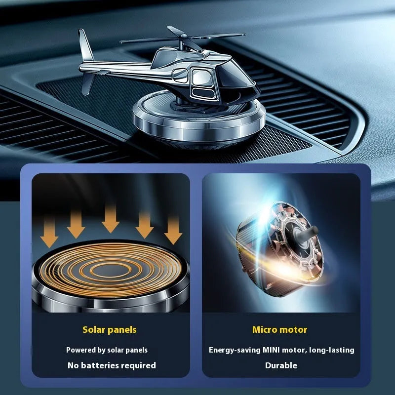 Silver solar-powered metal helicopter car air freshener ornament with spinning blades on a dashboard.