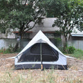 Brown ultralight A-frame hiking tent pitched with hiking poles in an outdoor setting