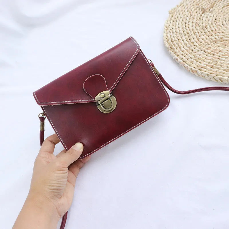 Soft surface crossbody messenger bag with flap closure and lock hardware in wine red colour