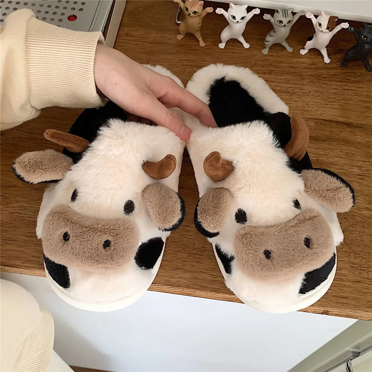 White women's cow pattern slippers made of soft faux fur with textured anti-slip soles.