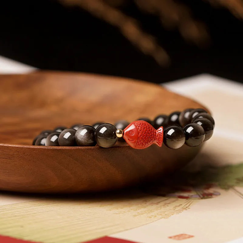 Natural black obsidian round bead bracelet with red cinnabar fungus decorative elements.