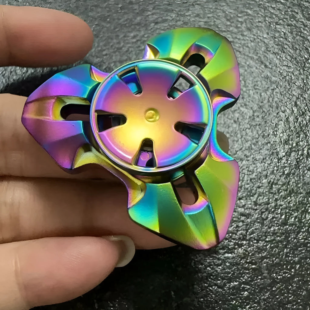 Alloy metal fingertip gyro decompression toy in gun metal colour, spinning on a surface.