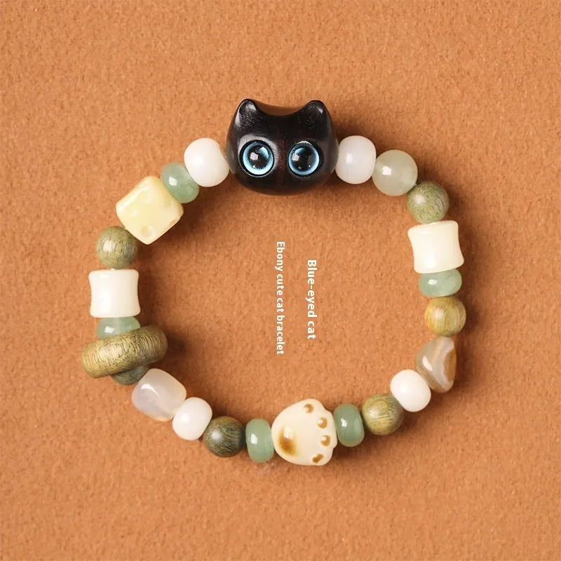 Hand-woven cat paw bracelet with a jade, bodhi seed, and ebony multi-treasure cube charm.