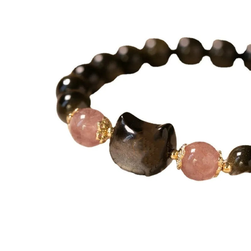 Black obsidian beaded bracelet with silver kitty cat charms on a wrist.