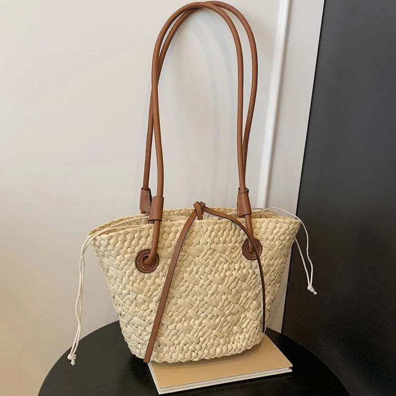 A retro-style horizontal square woven bag in milky white, shown being carried by hand.