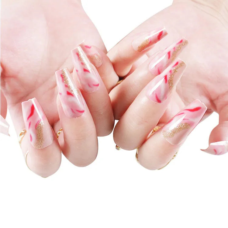 Set of pink press-on artificial nails with rose pattern, shown next to a bottle of nail glue.