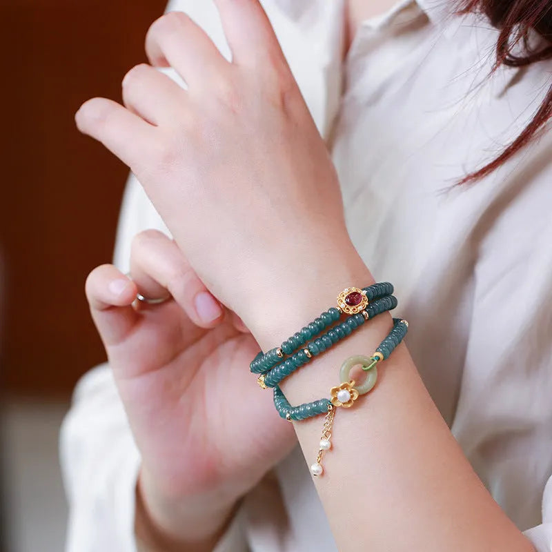 Close-up of a women's blue water jade abacus bead bracelet with three rings, tourmaline, and pearl accents.