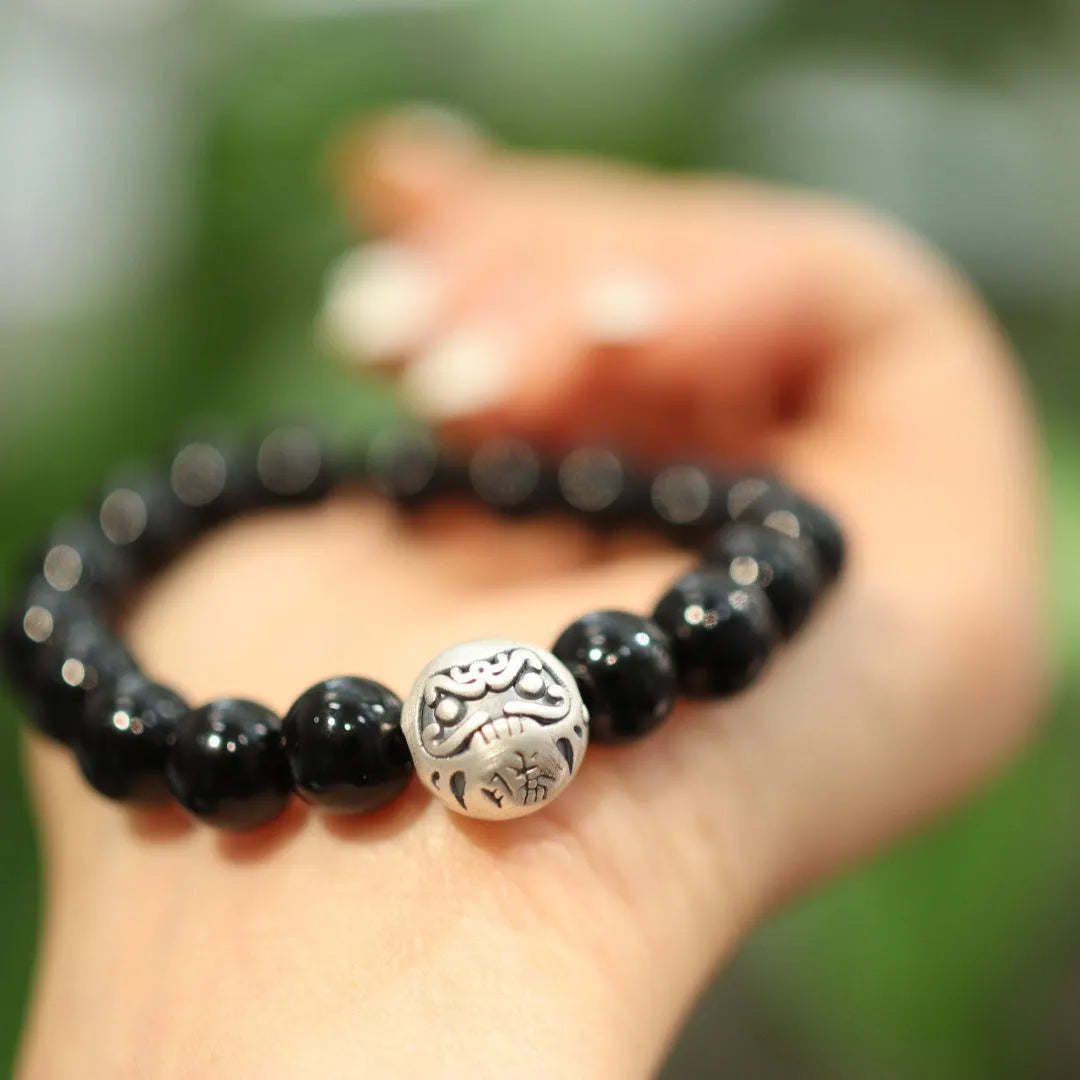 Close-up of a women's black agate bracelet with a sterling silver clasp on an alloy chain.