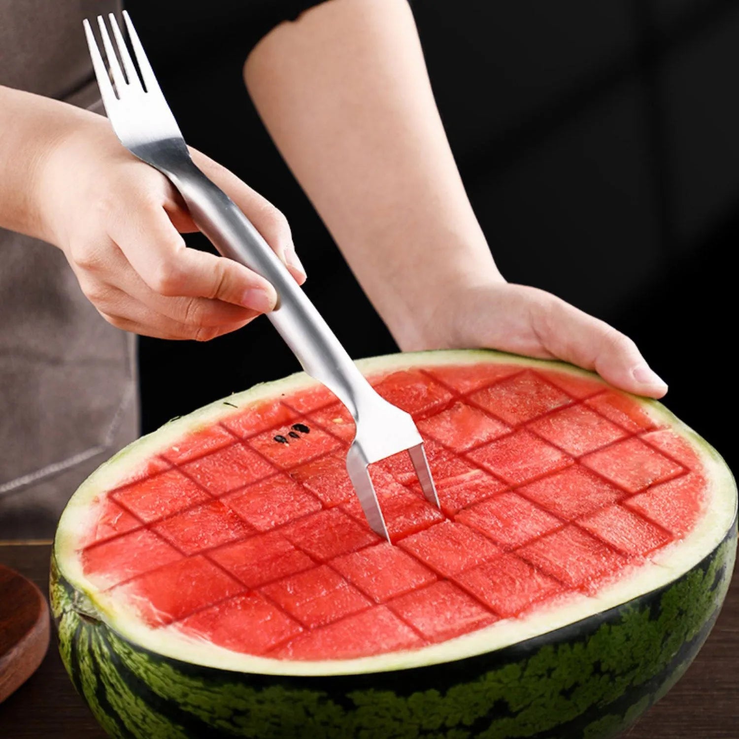Stainless steel watermelon slicer and fork tool on a kitchen surface