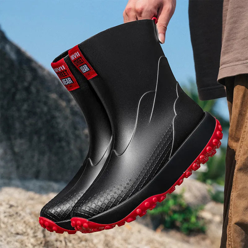 Men's black and red PVC rain boot with a round toe and non-slip plastic sole on a wet surface.