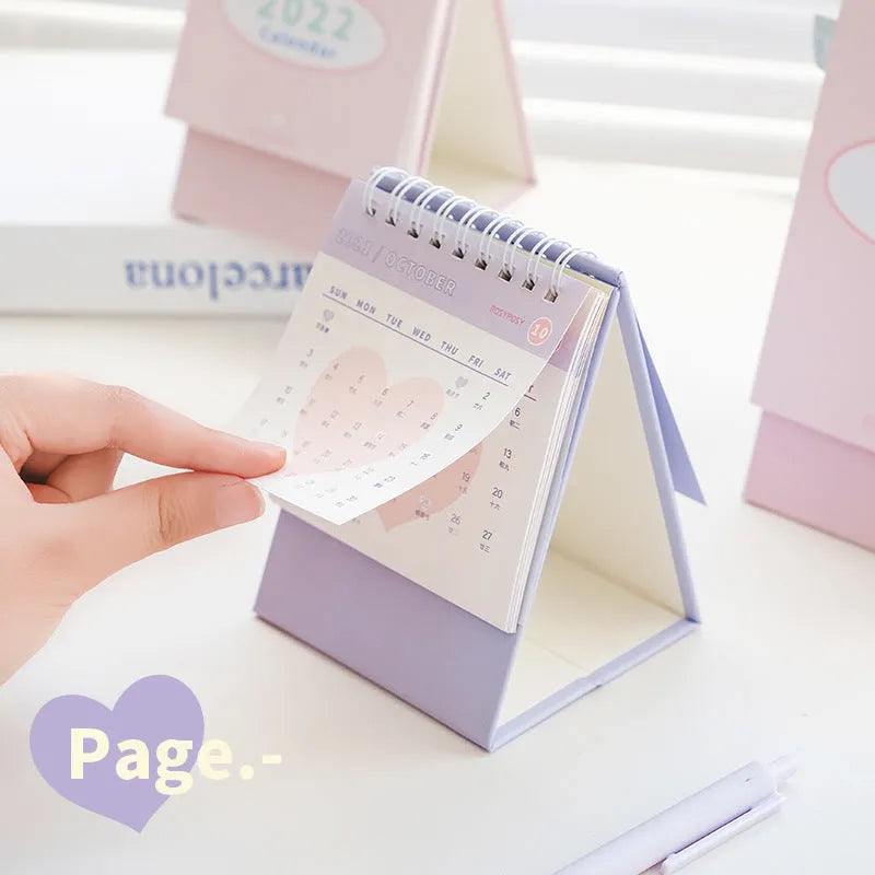 Cream coil-bound desk calendar for 2022, paper, Regular size, on a desk with month view visible