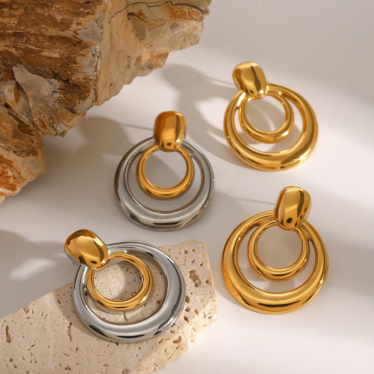 Golden round geometric stud earrings with hollow double layer design on white background