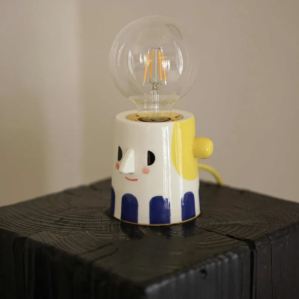 Handmade white ceramic table lamp with a creative ball headlight design on a wooden surface.