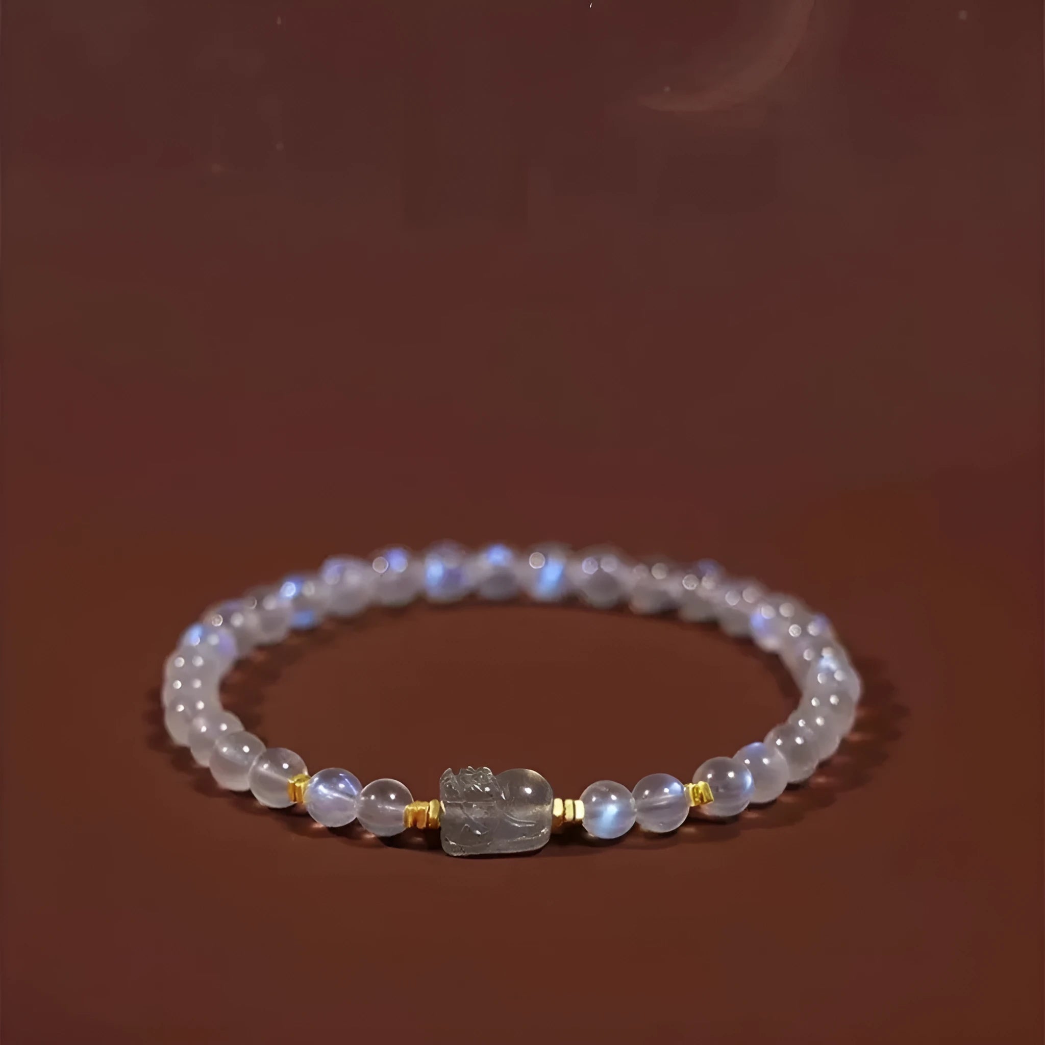 Close-up of a moonstone bracelet with a carved animal or zodiac design, showing grinding finish and blue light trend detail.