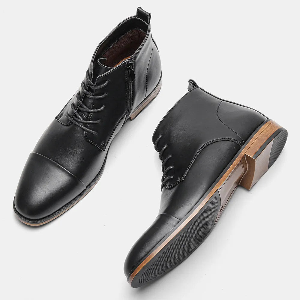 Men's black Chelsea boots with a side zipper, round toe, and low heel on a wooden sole.