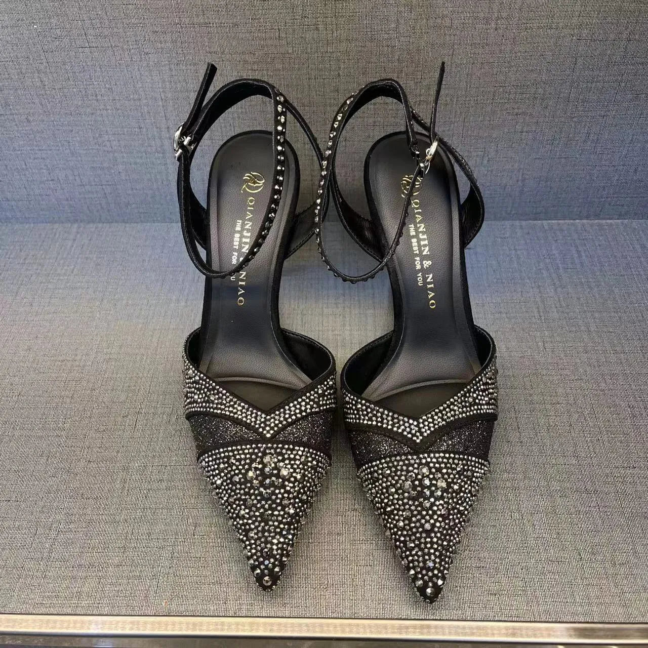 A pair of women's black hollow high heels with a red sole, stiletto heel, and pointed toe.