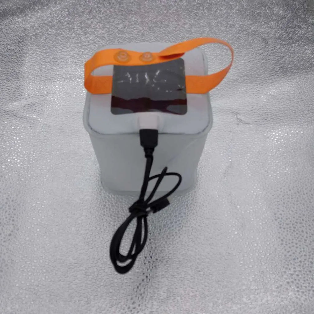 White solar inflatable waterproof camping LED lantern with handle, collapsed flat on a table