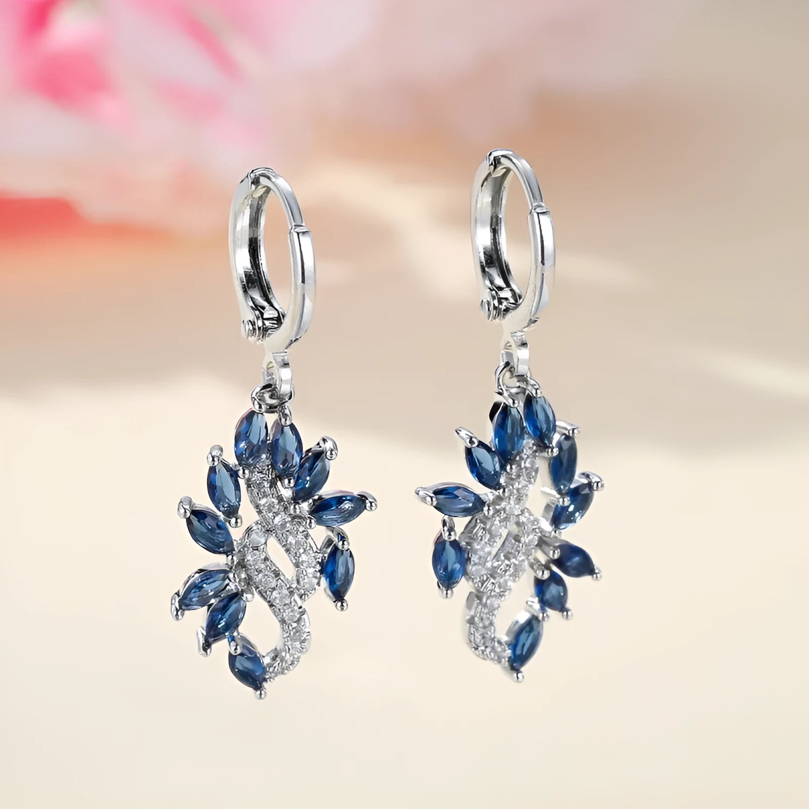 A pair of platinum sapphire blue alloy drop dangle earrings for women on a plain background.