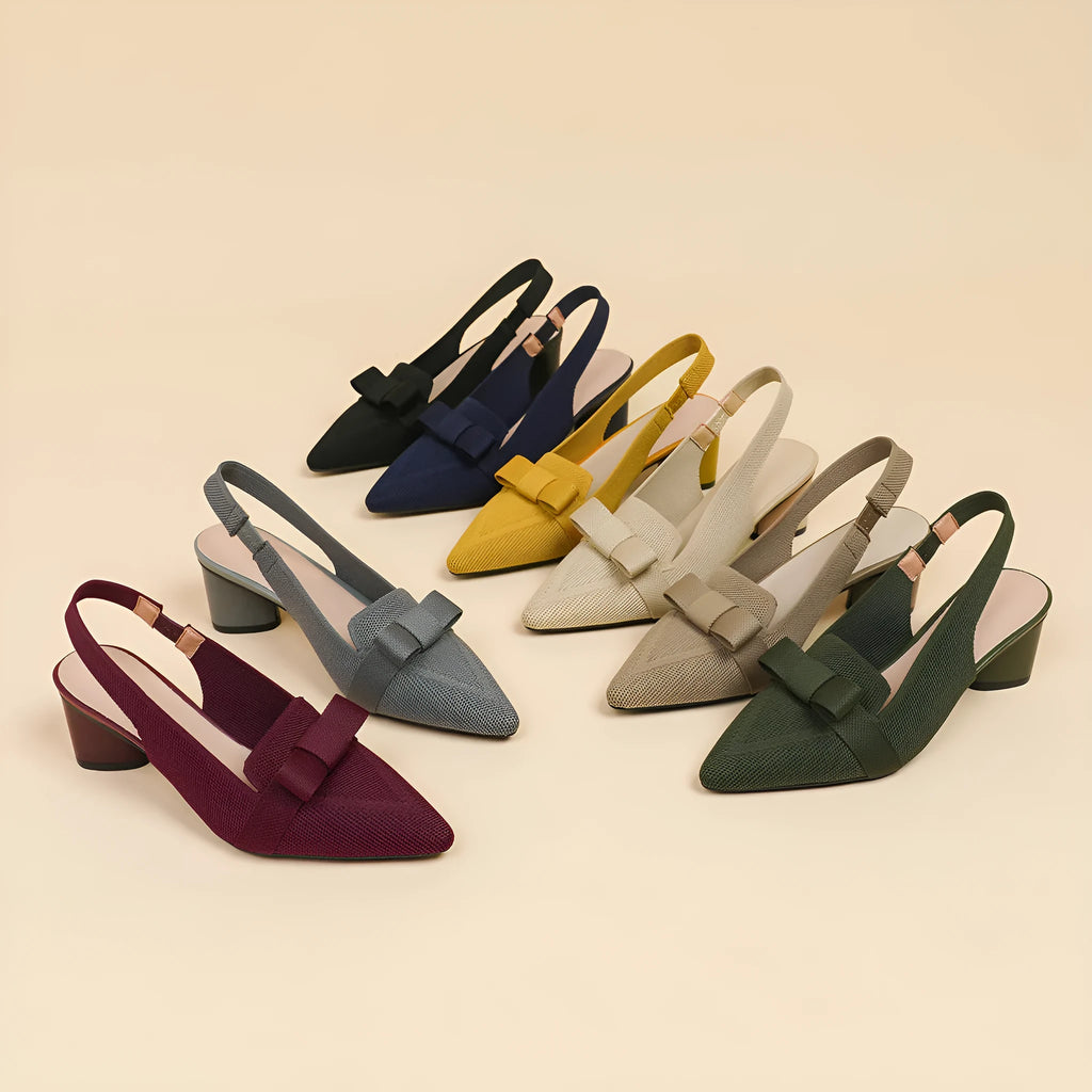 Women's closed toe high heel sandals with bow detail, ankle buckle strap, and pointed toe in a solid colour.