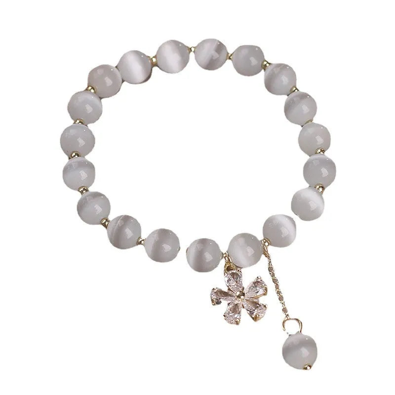 White cat's eye stone women's bracelet with a safety buckle and small flower tassel.