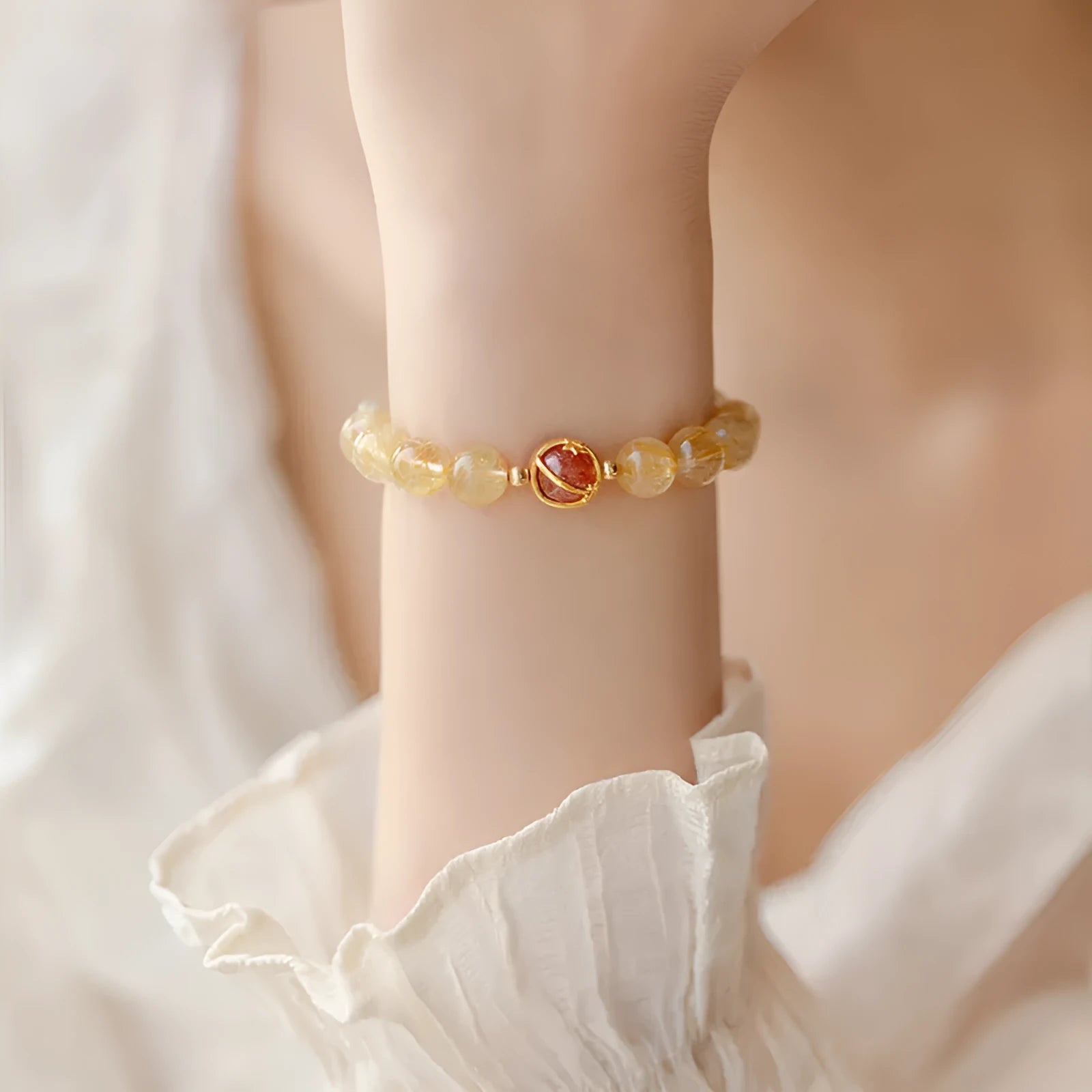 Citrine and gold rutilated quartz bracelet with diamond-cut beads in 6mm or 8mm size on a wrist.