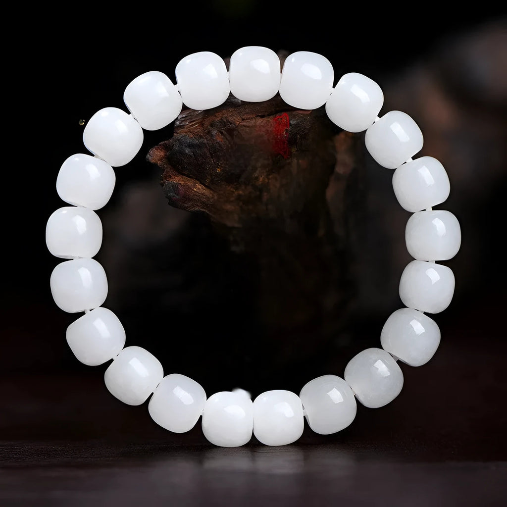White Hetian jade barrel bead bracelet for men and women on a wooden surface.