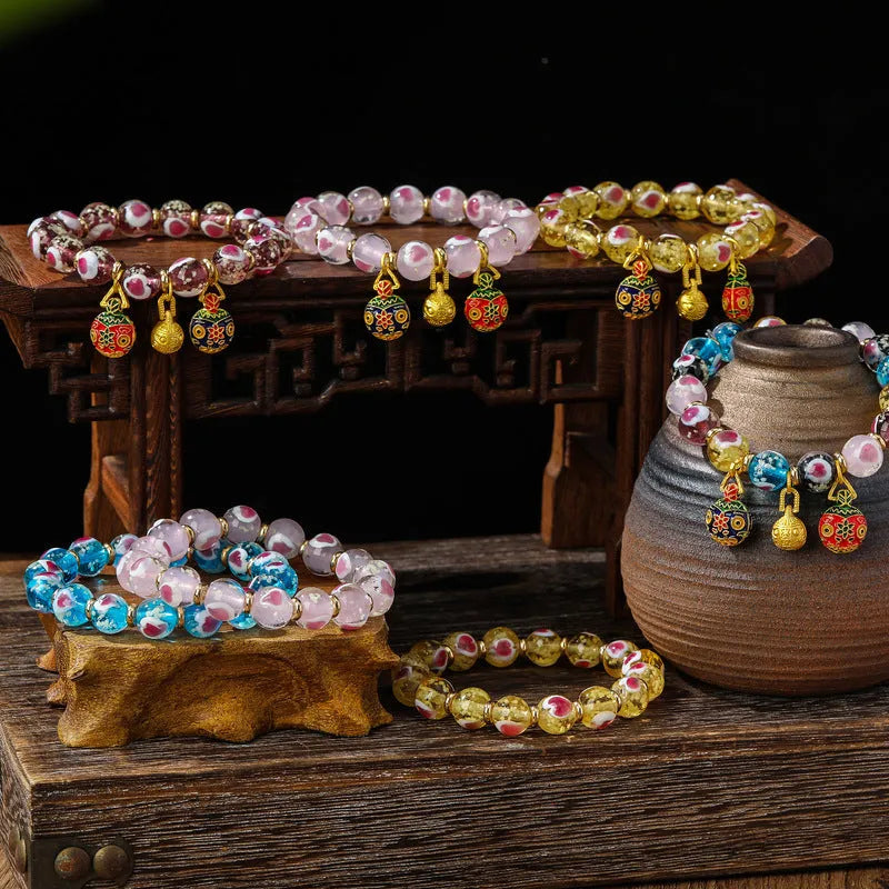 Glass bracelet with 10mm heart beads featuring ancient swallowing gold beast design in multiple colours