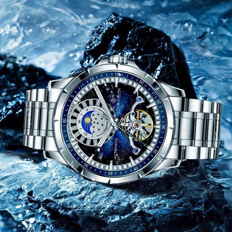 Men's silver automatic mechanical watch with blue dial and stainless steel bracelet on wrist.