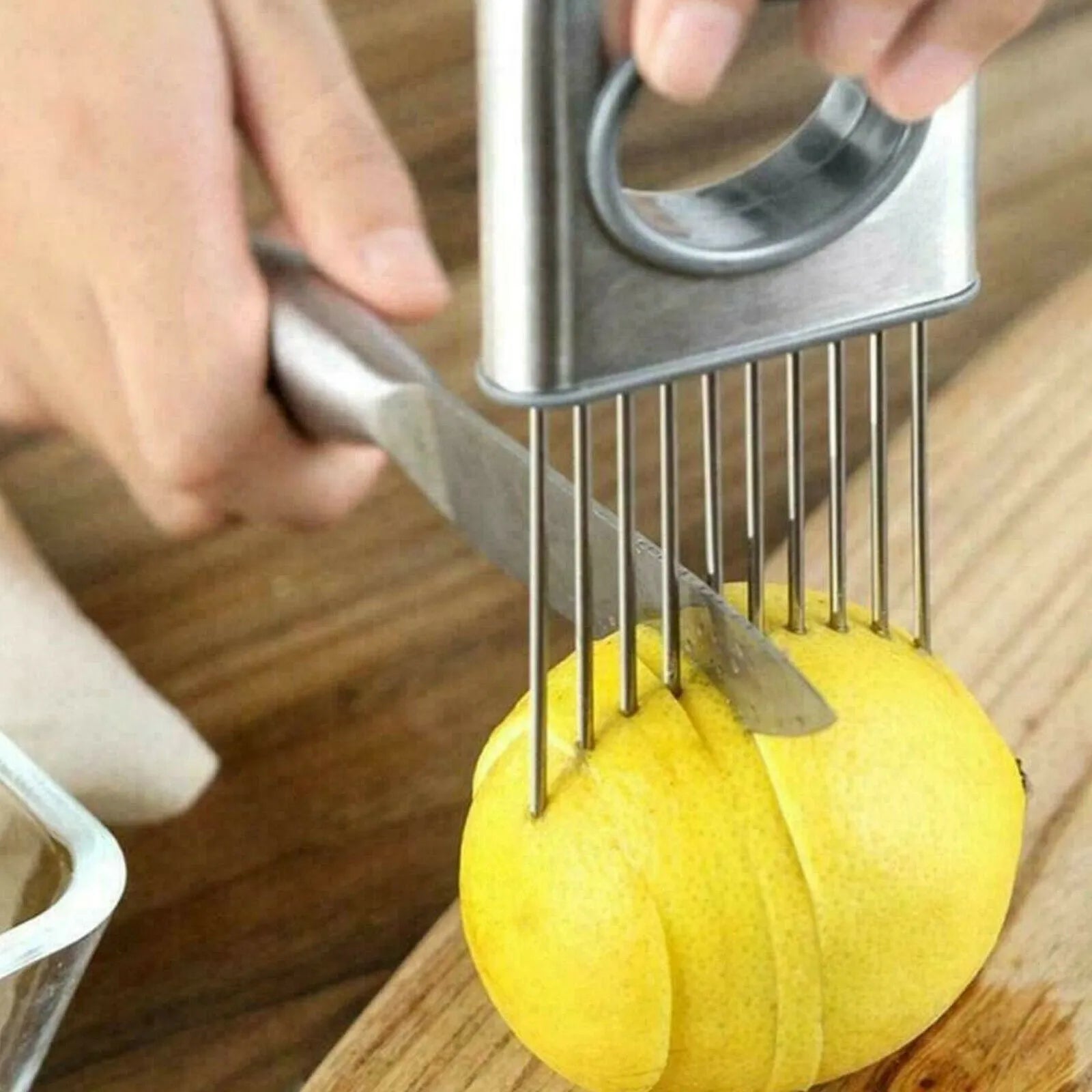 Stainless steel onion holder slicer with sharp prongs and a red finger guard on a cutting board.