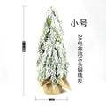 Small 24-inch frosted artificial Christmas tree with LED lights on a desktop.