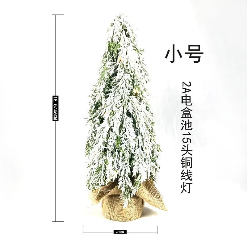 Small 24-inch frosted artificial Christmas tree with LED lights on a desktop.