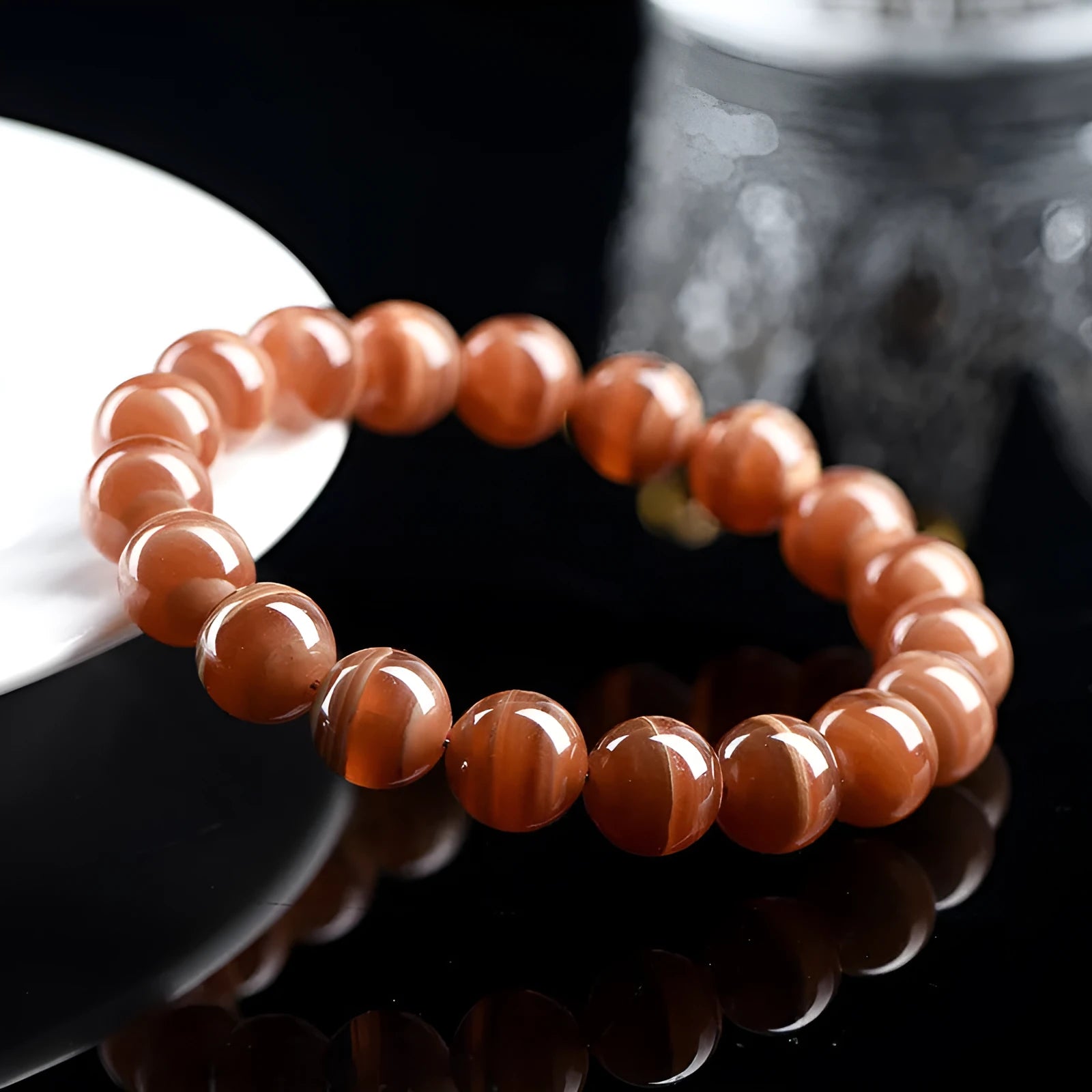 Natural old mine rhodochrosite round bead bracelet with geometric and Ruyi design on a wrist.