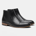 Men's black Chelsea boots with a side zipper, round toe, and low heel on a wooden sole.