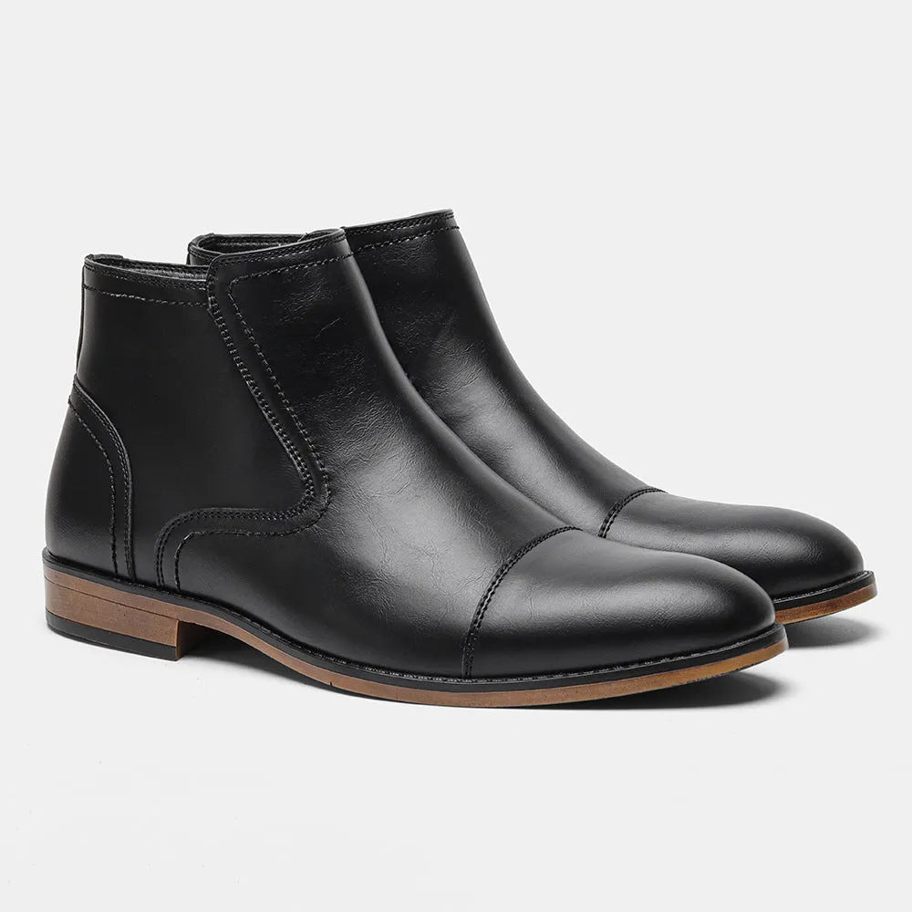 Men's black Chelsea boots with a side zipper, round toe, and low heel on a wooden sole.