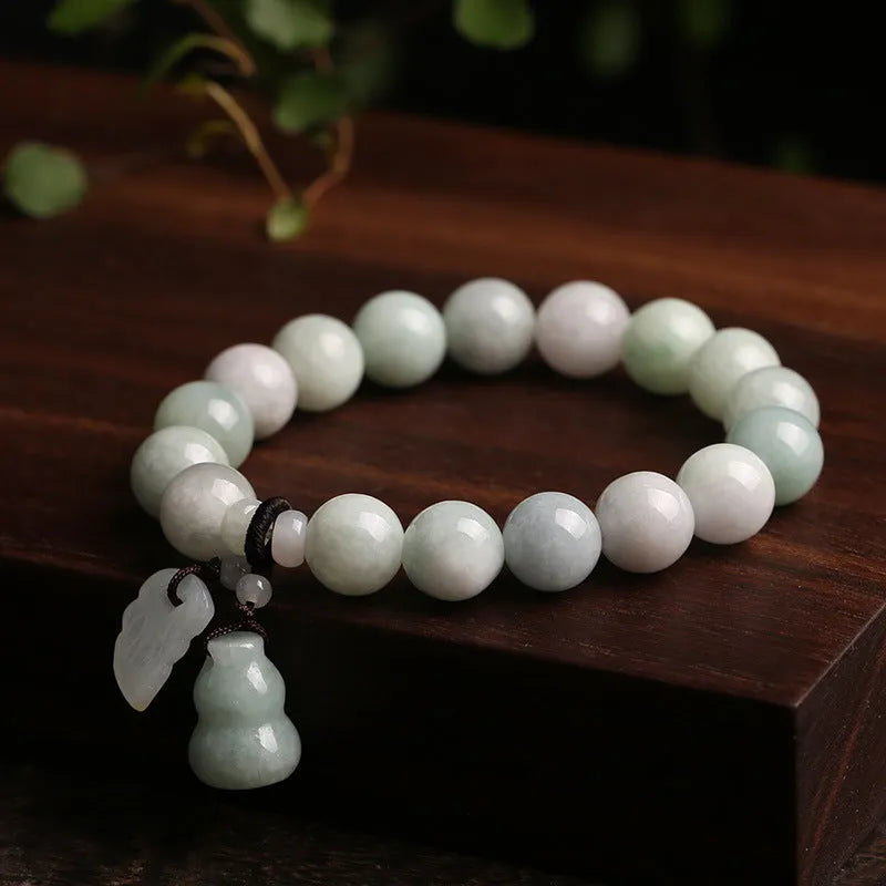 Natural green jade bracelet with a geometric shape and a hanging apple charm on a white background.