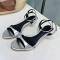 Women's black leather open toe sandals with a kitten heel and buckle fastening, retro Roman style.