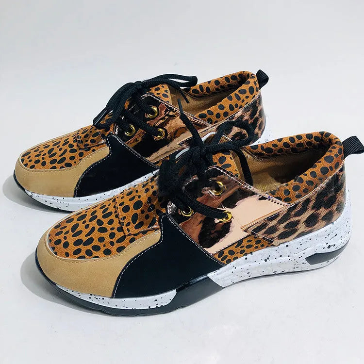 Women's black suede casual sneakers with a wedge heel on a wooden floor.