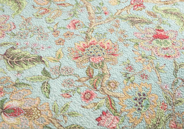 Blue American floral pattern cotton quilted bedspread set of three pieces laid on a bed.
