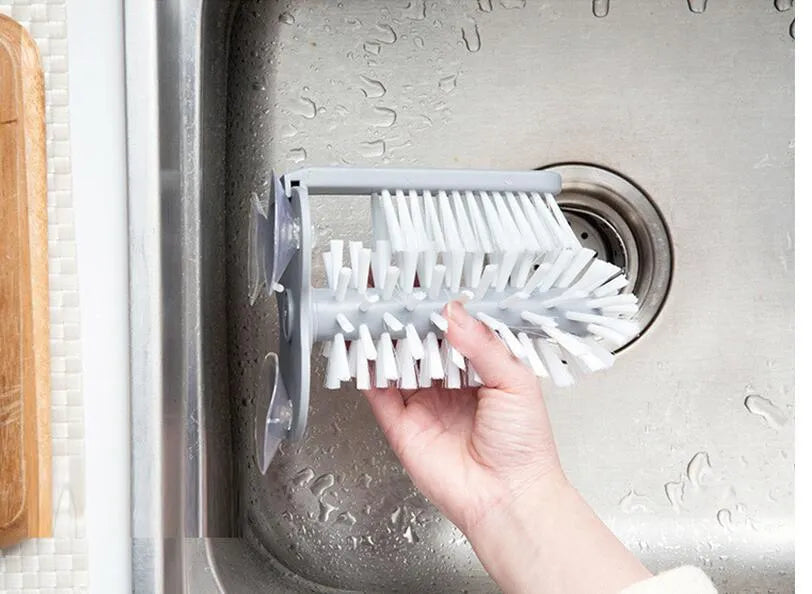 Grey kitchen cleaning brush with two brush heads and suction cups for wall mounting