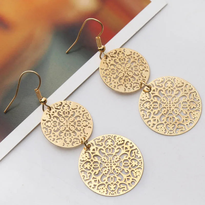 Women's round hollow gold drop earrings with dangle design on a light background