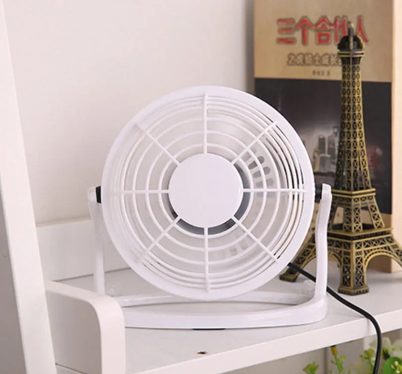 Small black adjustable USB desk fan with key switch on a wooden table.