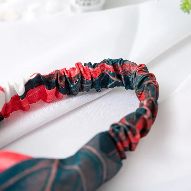 Red cloth headband with banana leaf pattern for women, showing elastic band construction