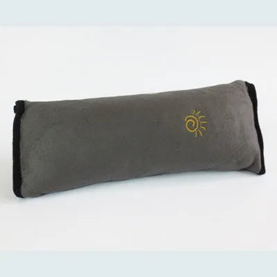 Children car pillow in grey micro-suede fabric attached to a car seat belt shoulder strap
