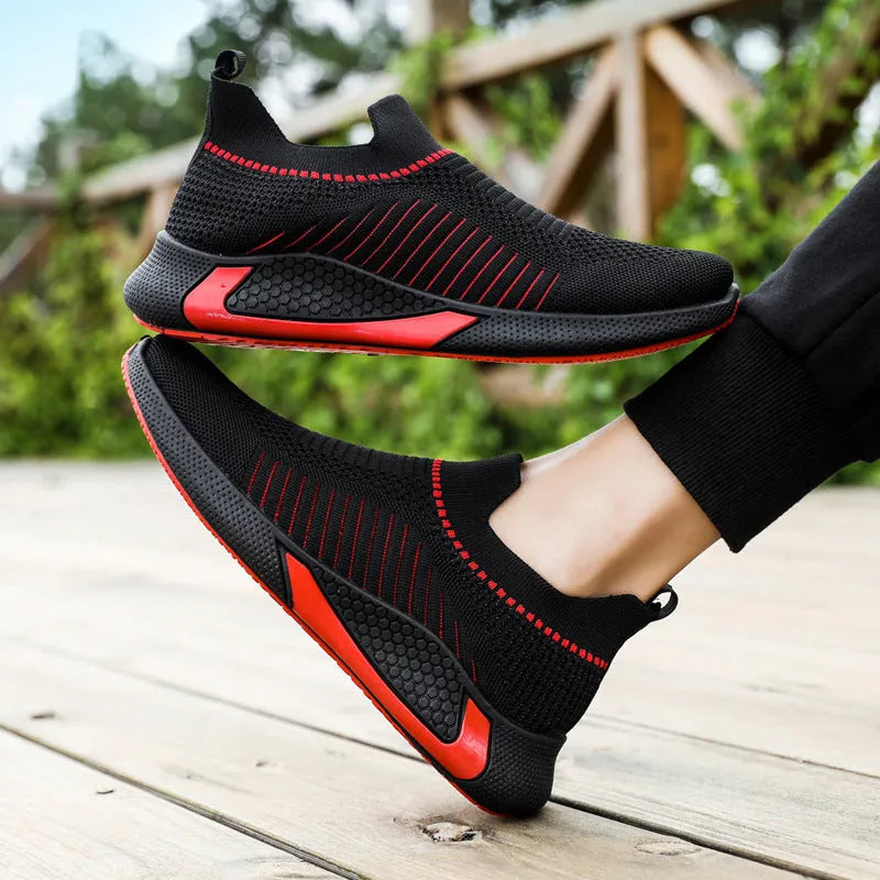 Men's black and white striped mesh slip-on sneakers with flyknit upper and low-cut profile.